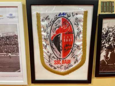 Naturalmente anche il Bari di De Laurentis � presente in questo museo. Oltre a varie t-shirt ufficiali c�� ad esempio un gagliardetto biancorosso autografato da tutta la rosa del 2018/19...